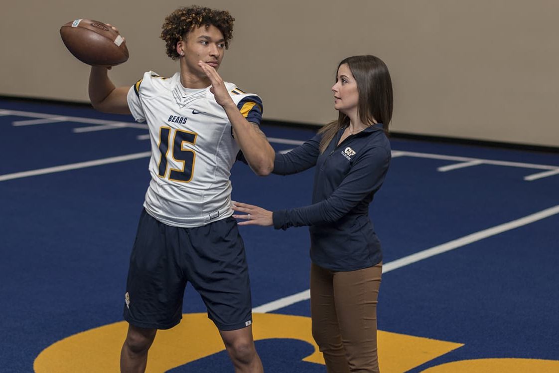 Image of Concordia St. Paul Kinesiology student working with a football player.