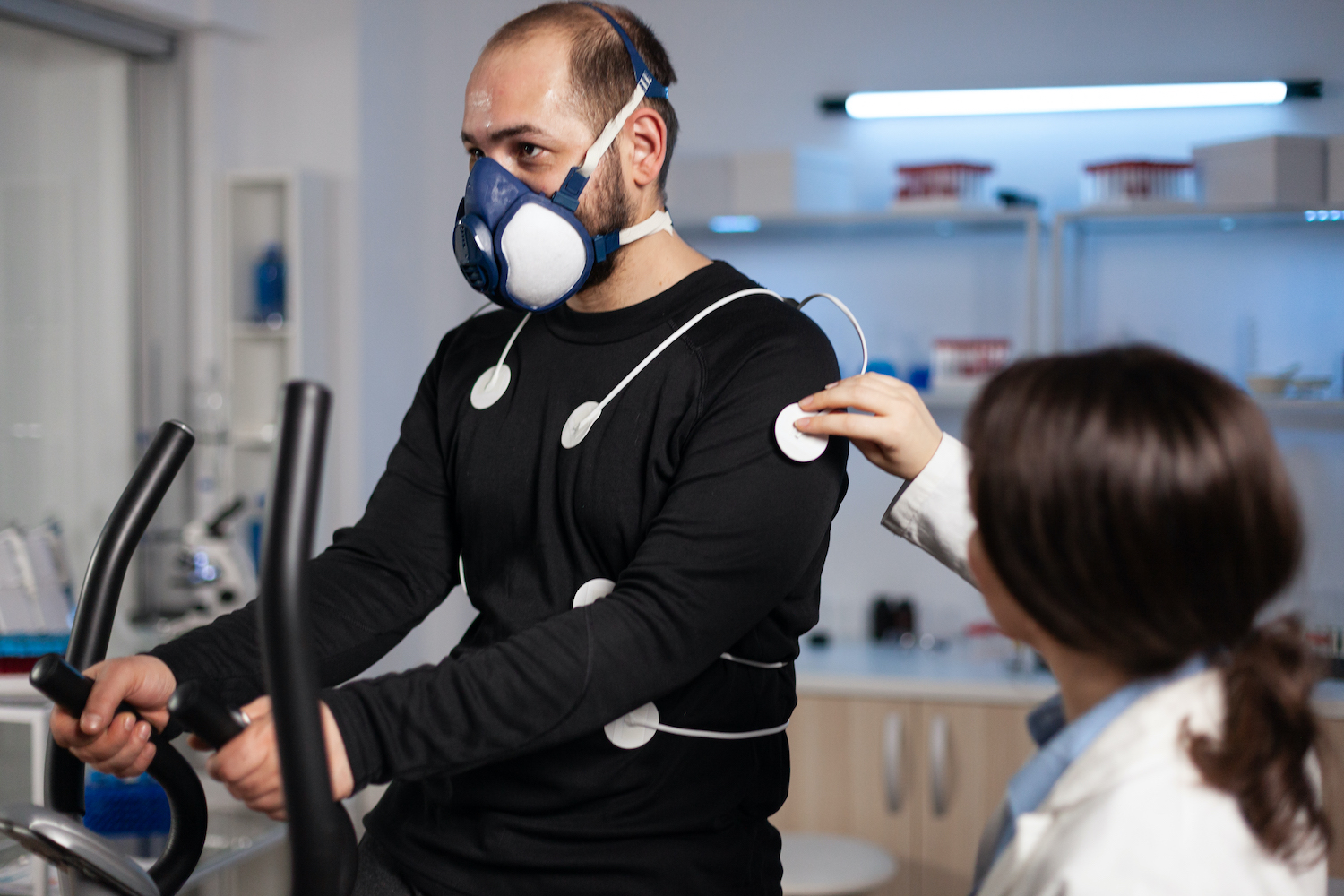 Specialist doctor physician putting electrodes sensor on sportman with mask
