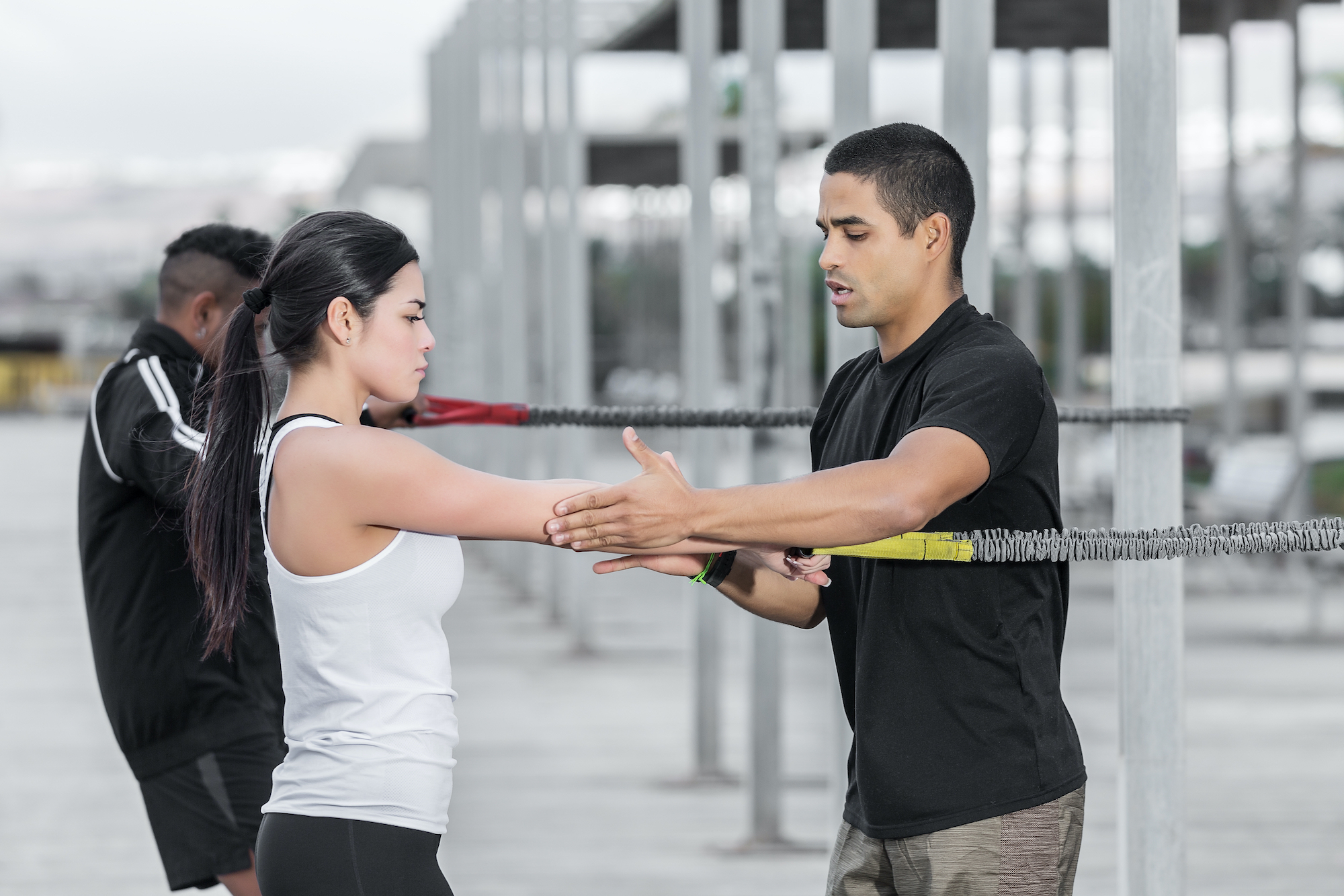 female training client being guided by male personal trainer