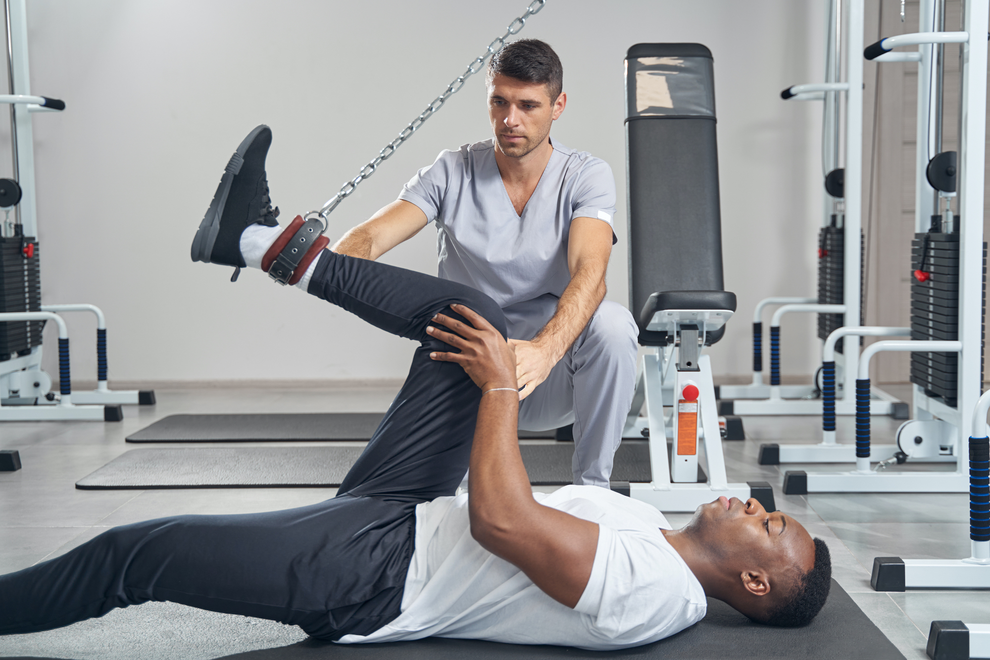 Man performing leg exercise supervised by physiotherapist