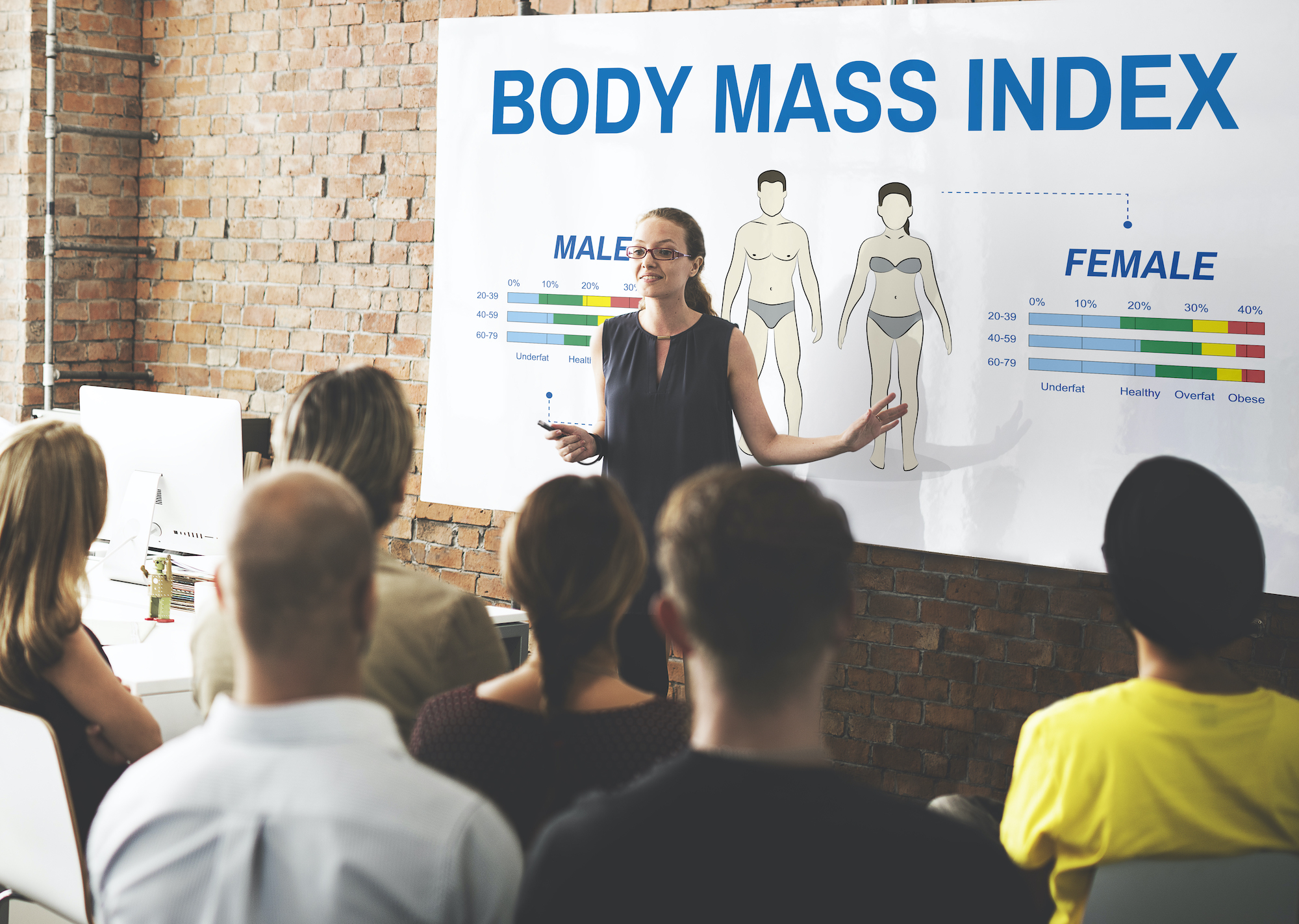 Female instructor leading a class full of adults on what Body Mass Index means.