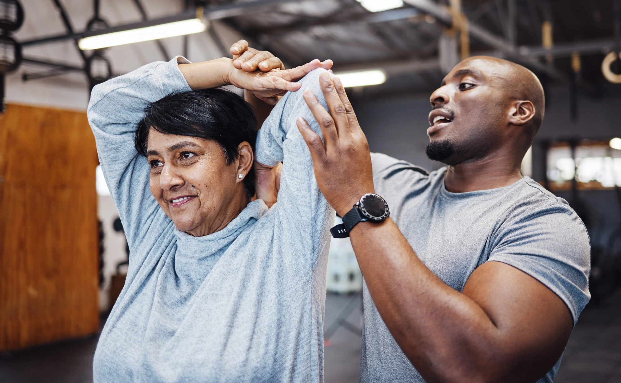 male assisting female stretching at a gym setting.