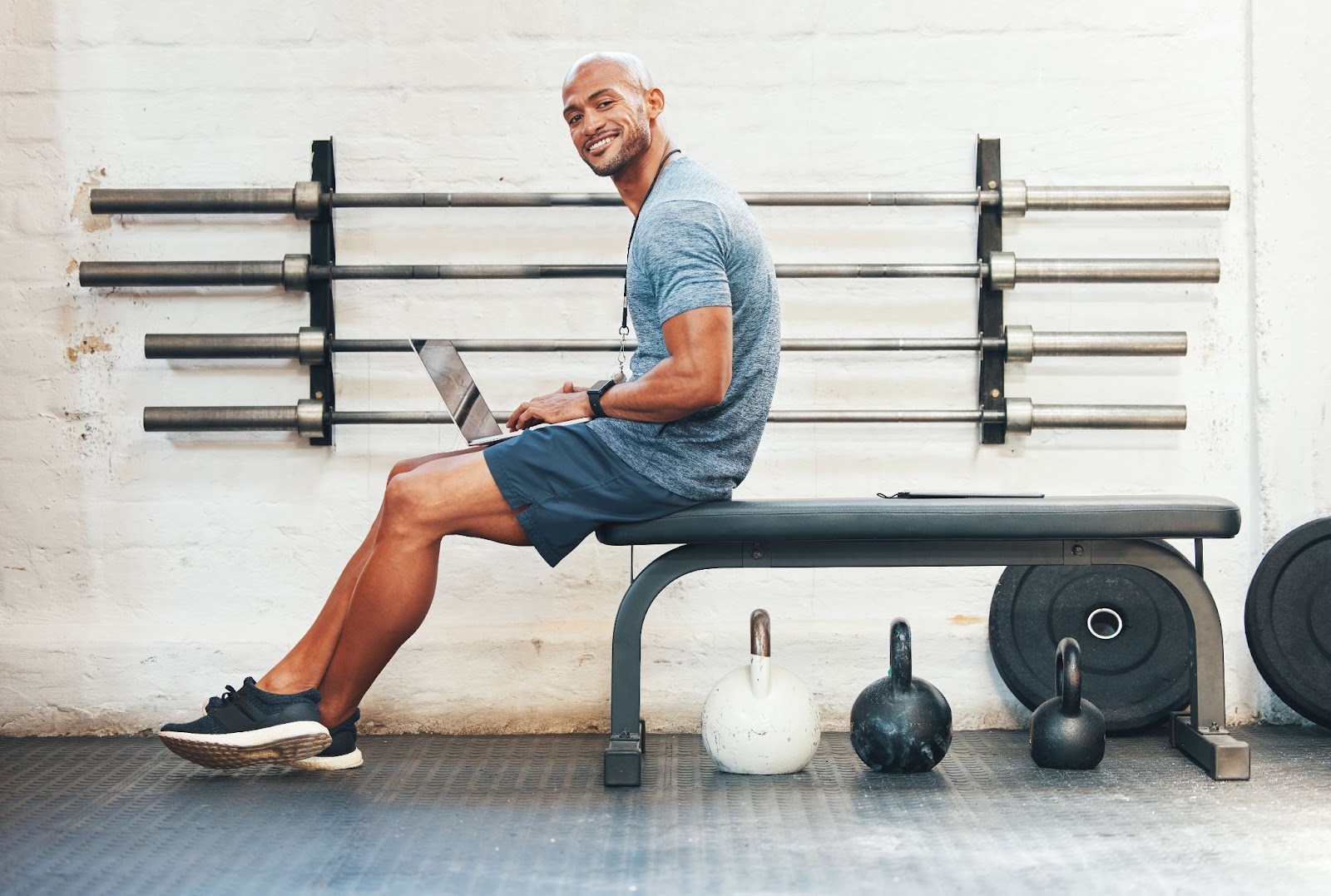 man working on laptop while sitting on workout bench