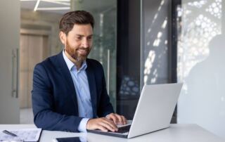 A professional man in business attire working on a laptop, representing high-paying careers in sports management, marketing, or analytics.